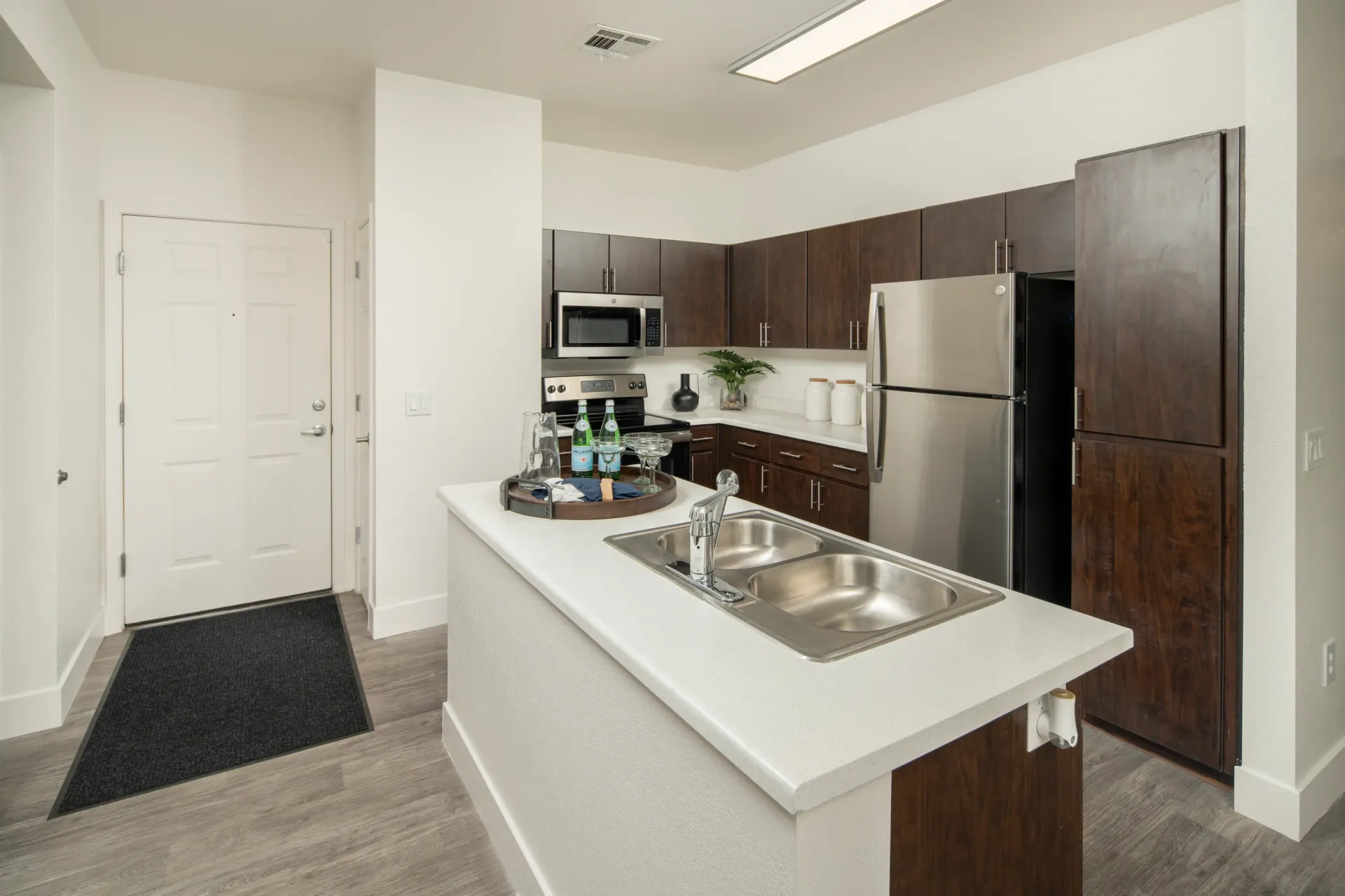 Modern kitchen with stainless steel appliances, dark wood cabinets, and a breakfast bar with a sink.