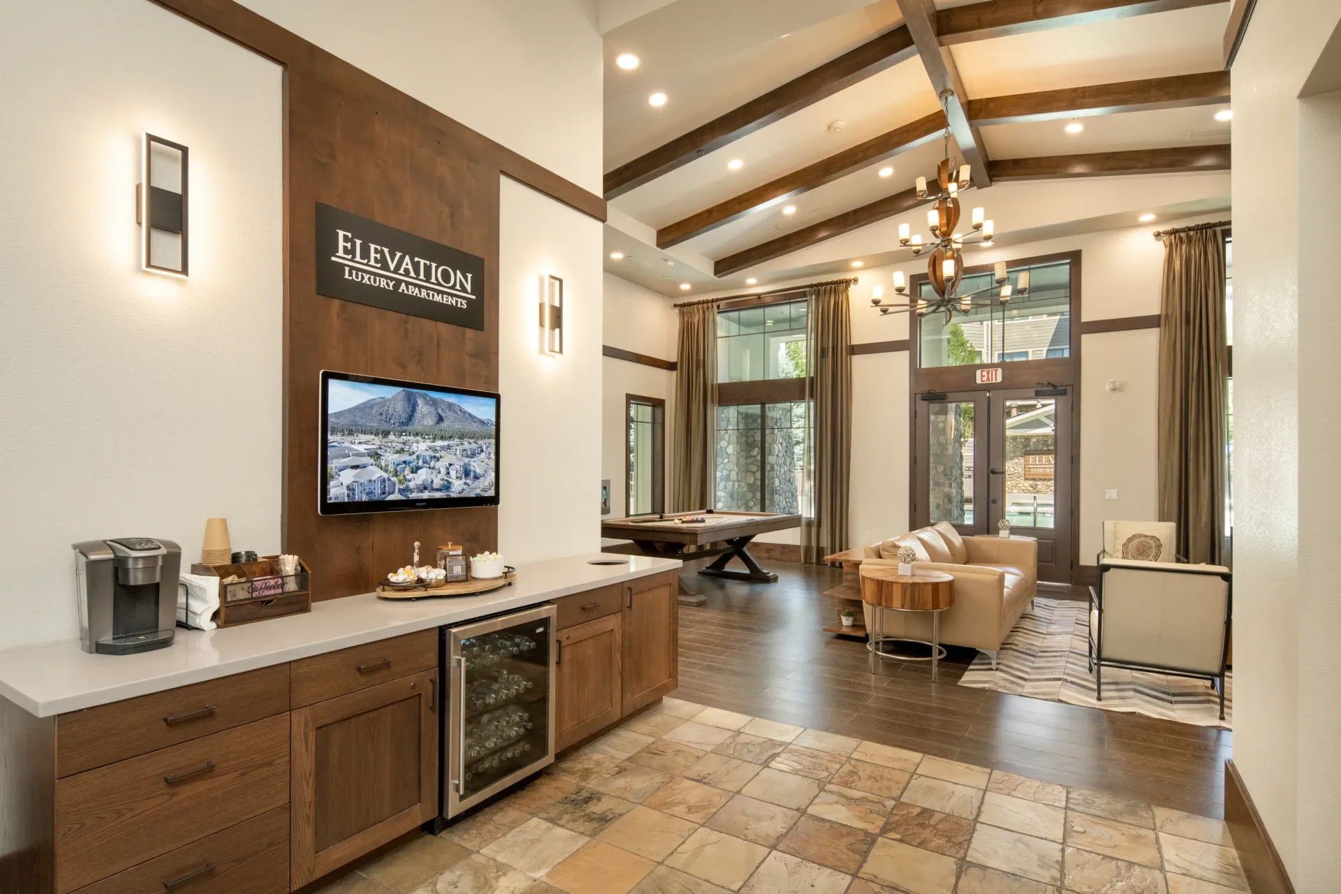 The lounge area of a luxury apartment complex, featuring a coffee station, a pool table, and comfortable seating at Elevation in Flagstaff, AZ.