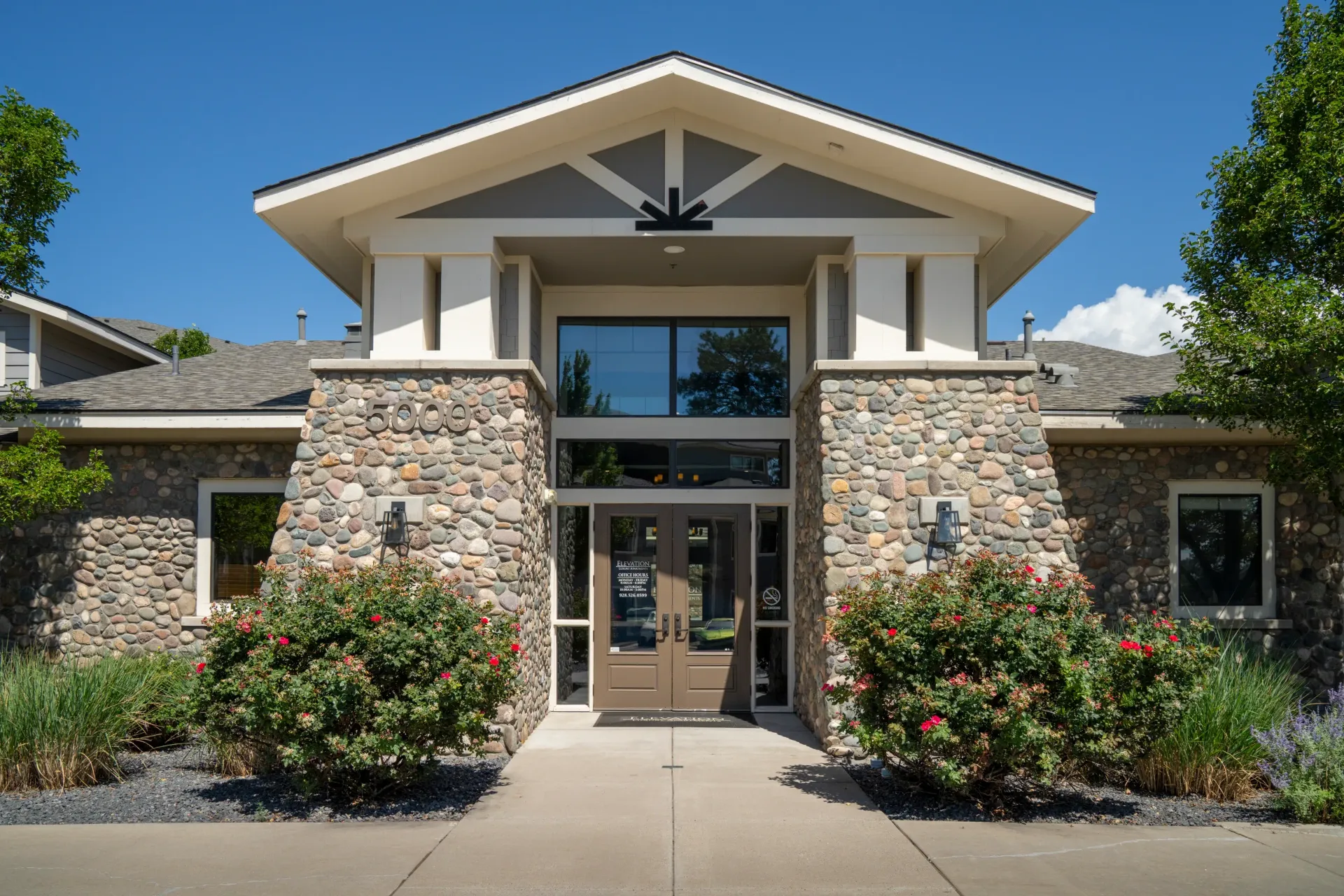 Entrance to a multifamily property with stone accents and lush landscaping at Elevation in Flagstaff, AZ at Elevation in Flagstaff, AZ.