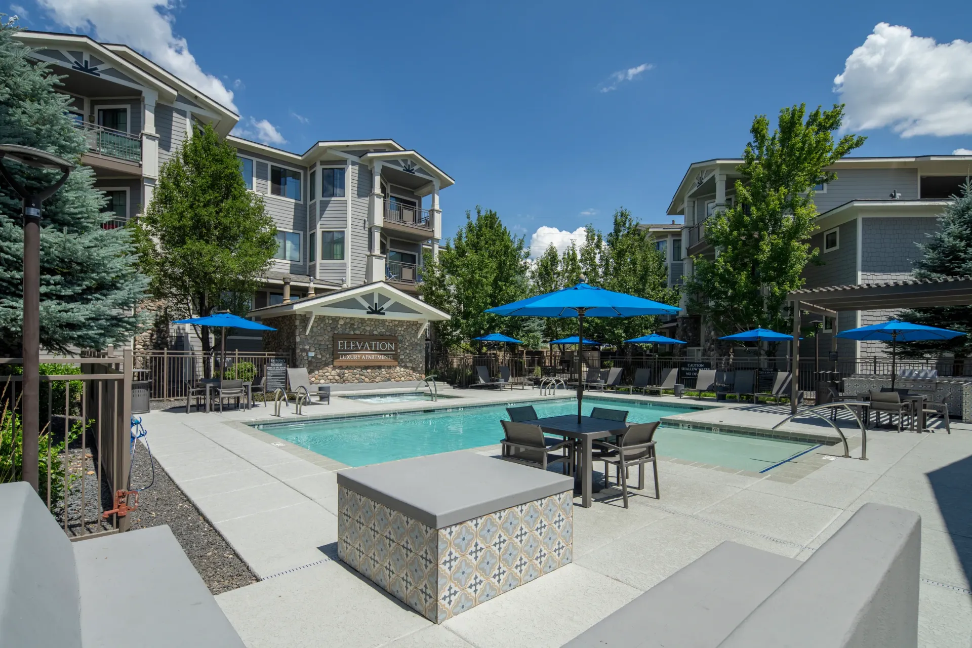 Resort-style swimming pool and hot tub area with lounge chairs and umbrellas.
