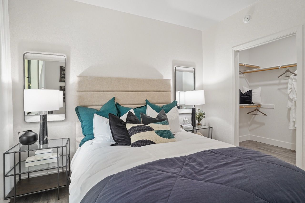 Bedroom with a large bed, teal accent pillows, nightstands, and an open walk-in closet.