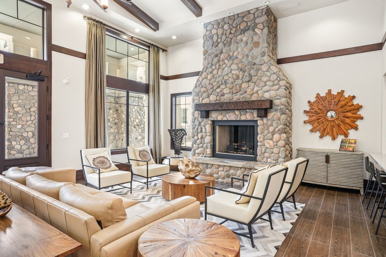 Spacious lobby-style living area with a stone fireplace, beige seating and large windows.