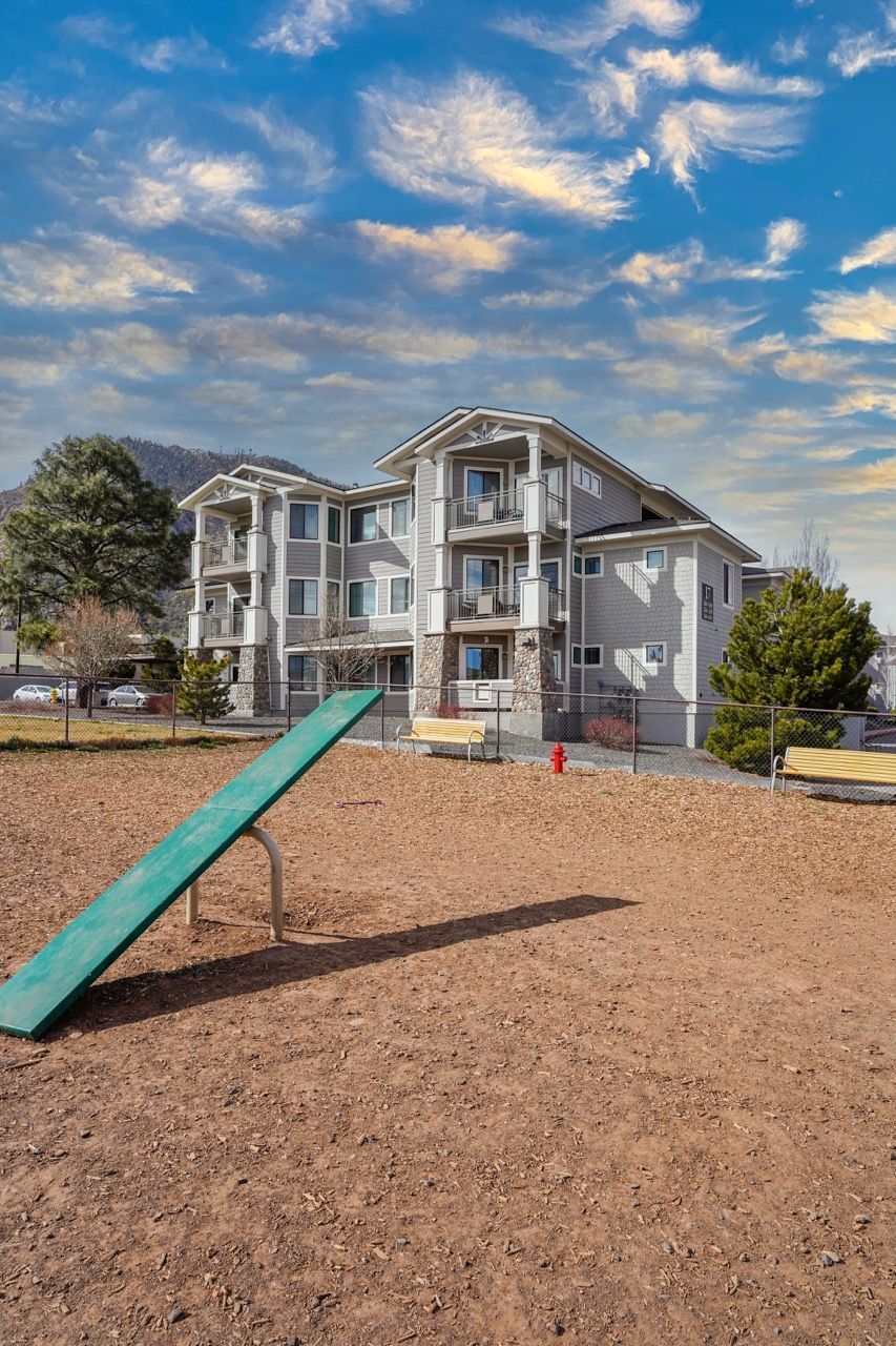 Exterior view of a modern apartment building with a playground ramp and benches.