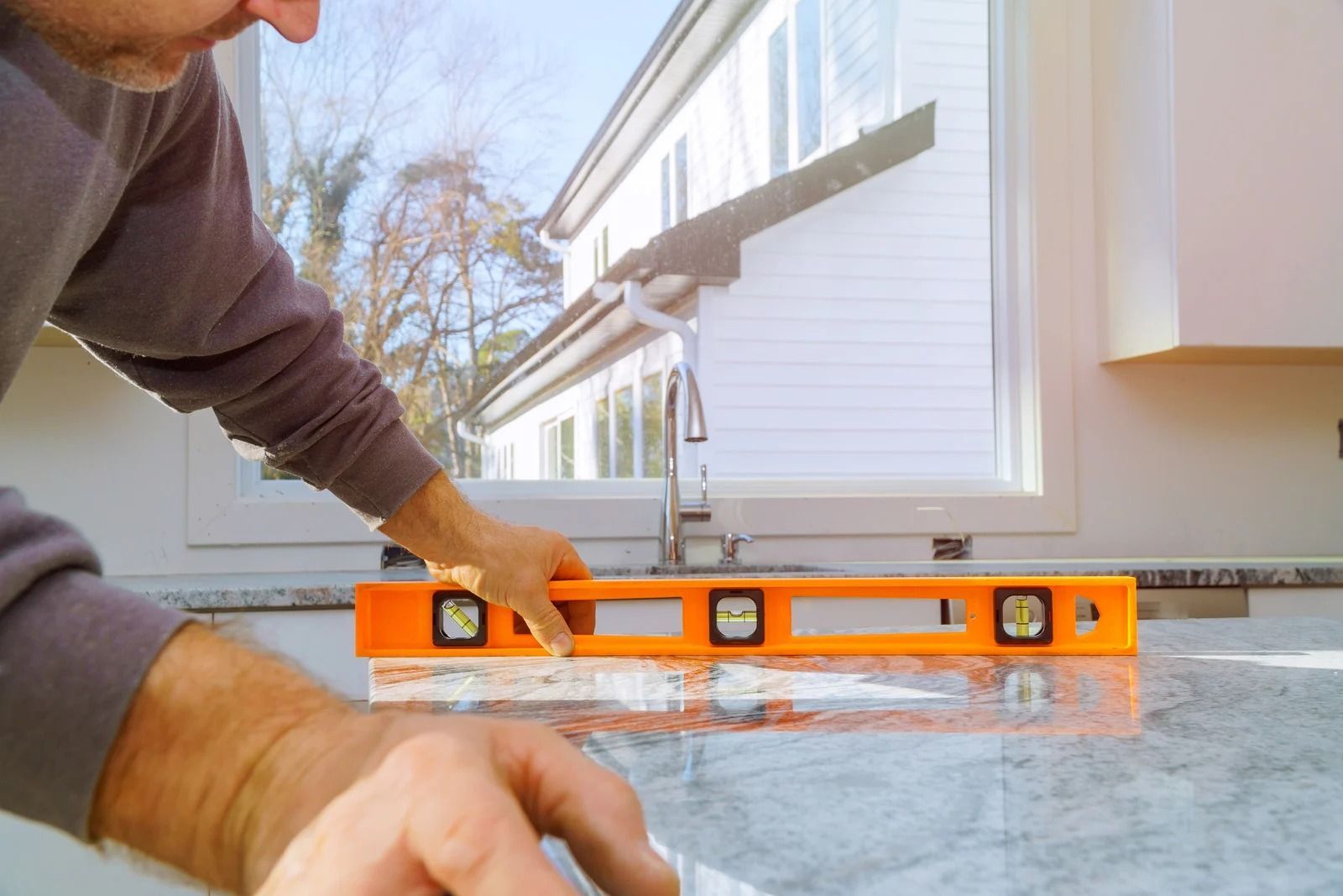 Person using a level on a countertop near a window.