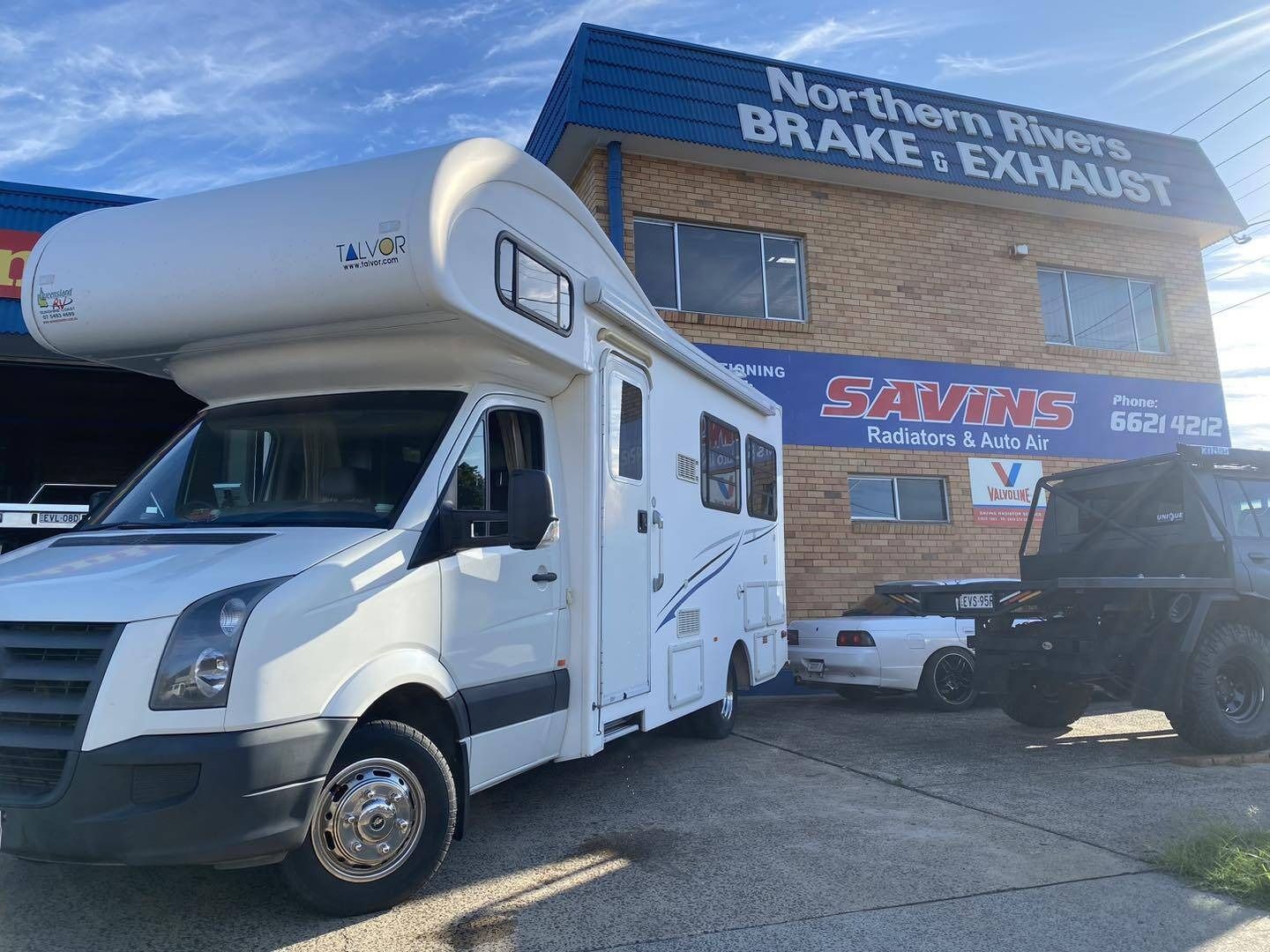 A White RV is Parked in Front of a Building — Savins Radiator Service In Lismore, NSW