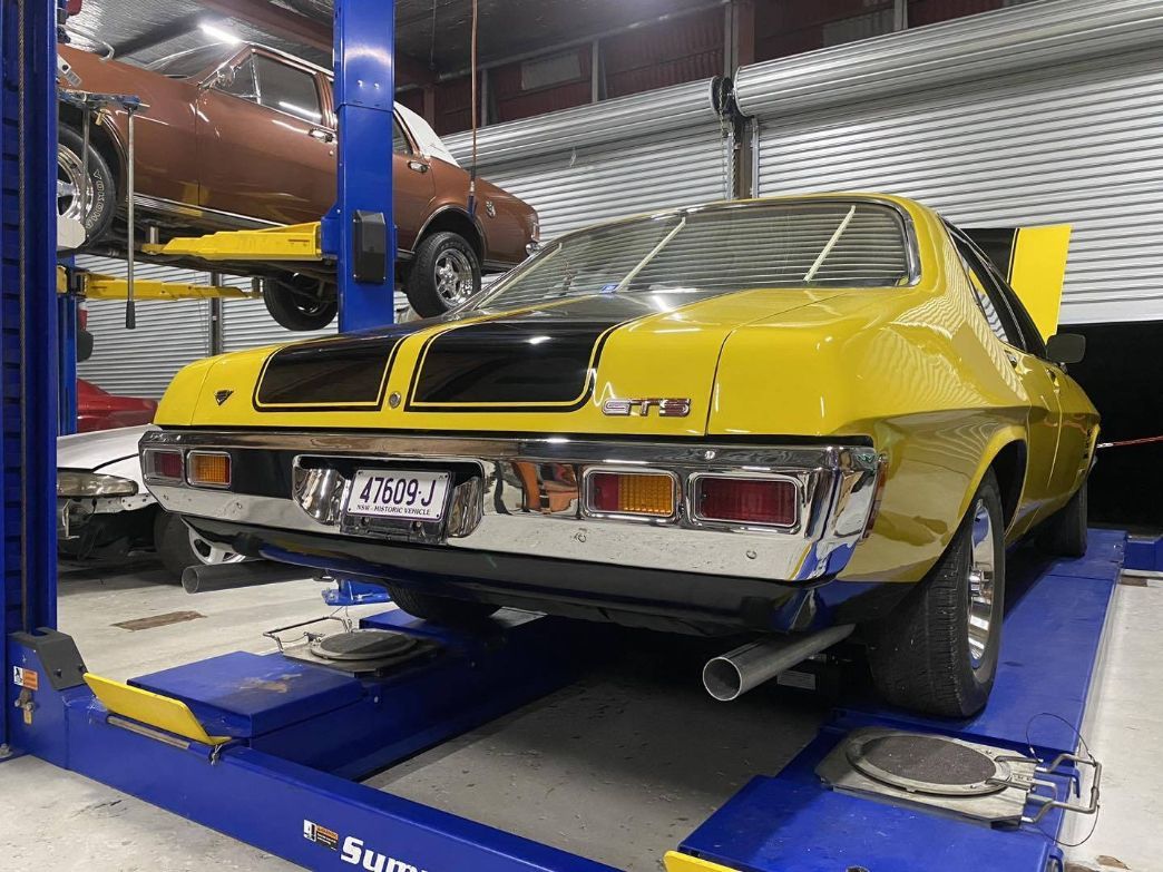 A Yellow Car is Sitting on a Lift in a Garage — Savins Radiator Service In Lismore, NSW
