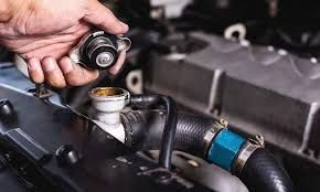 A Person is Holding a Radiator Cap Over a Car Radiator — Savins Radiator Service In Lismore, NSW