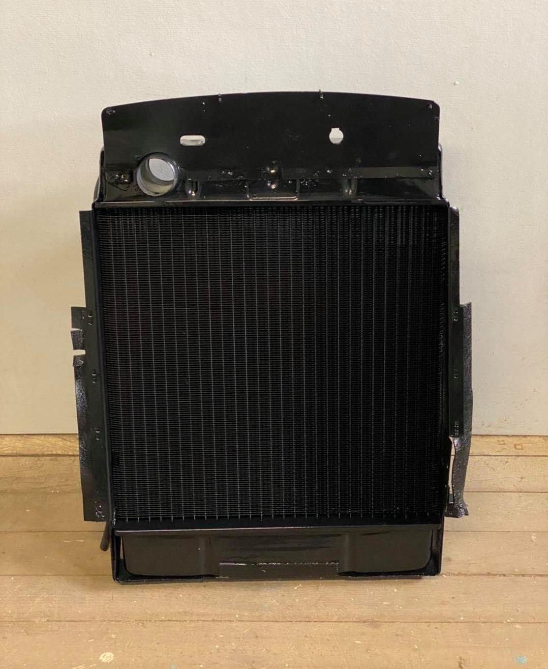 A Black Radiator is Sitting on a Wooden Floor — Savins Radiator Service In Lismore, NSW