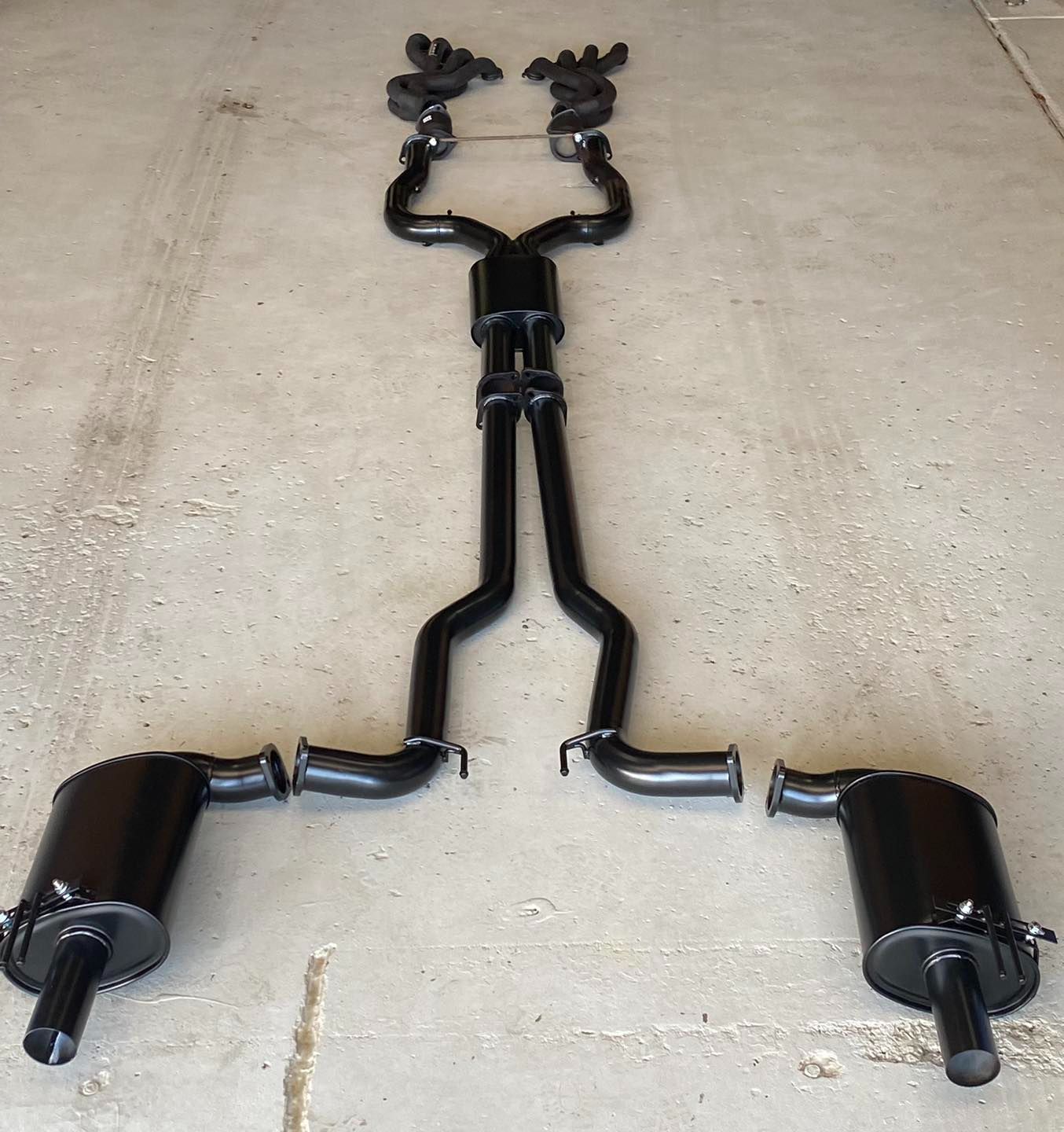 A Black Exhaust Pipe is Laying on the Ground — Savins Radiator Service In Lismore, NSW