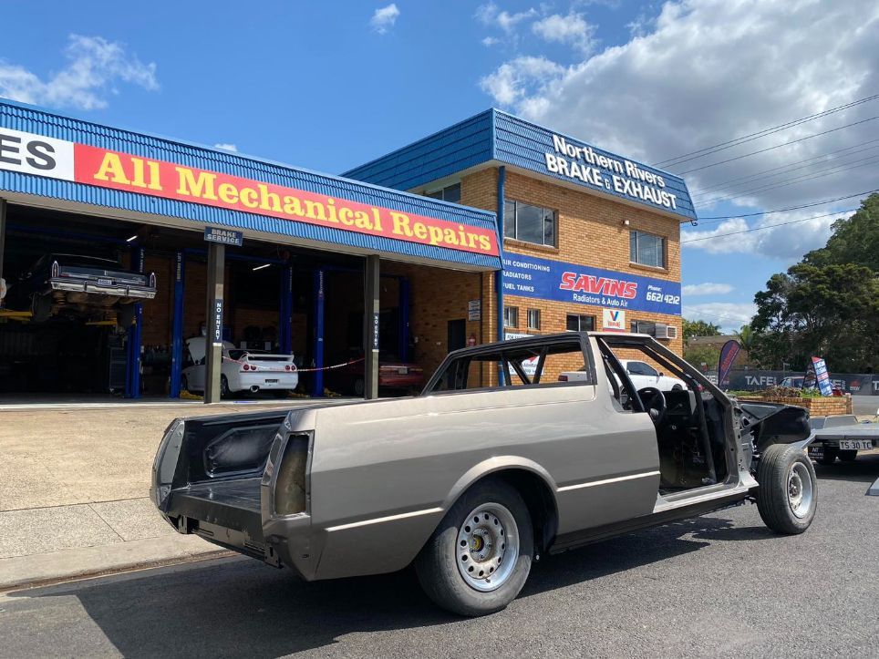 A Car is Parked in Front of a Building That Says All Mechanical Repairs — Savins Radiator Service In Lismore, NSW