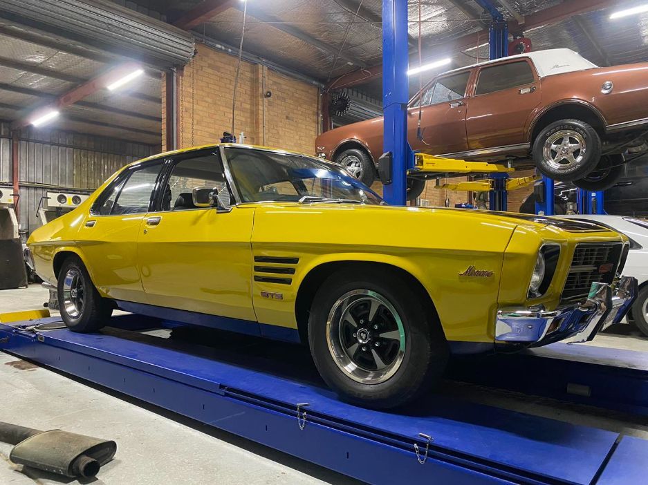A Yellow Car is Parked on a Lift in a Garage — Savins Radiator Service In Lismore, NSW
