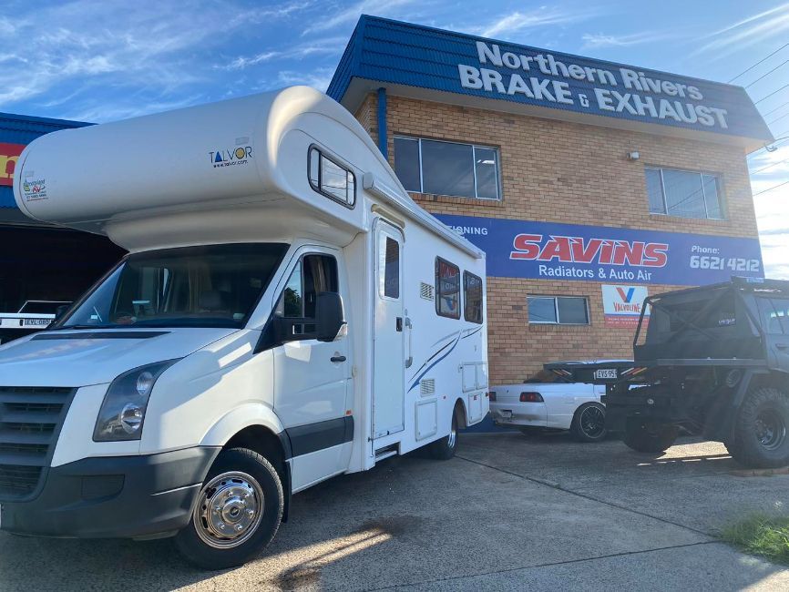 A White RV is Parked in Front of a Building — Savins Radiator Service In Lismore, NSW