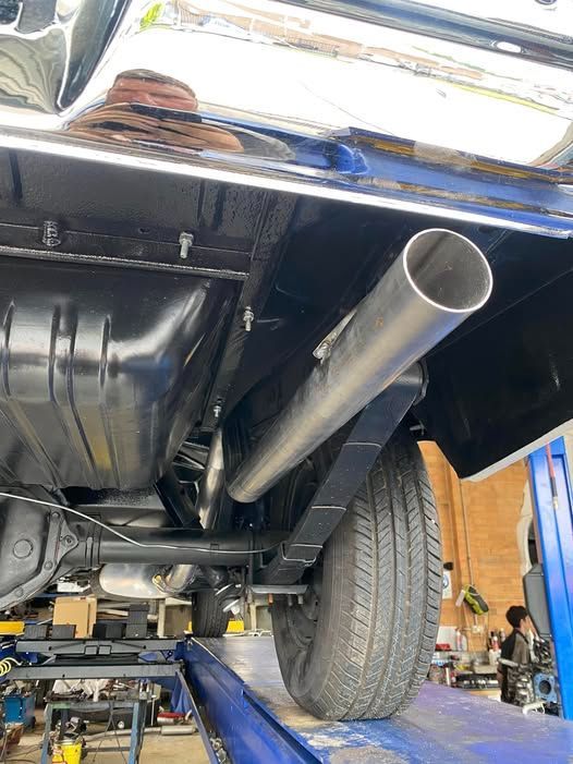 A Car With a Stainless Steel Exhaust Pipe is on a Lift in a Garage — Savins Radiator Service In Tweed Heads, NSW