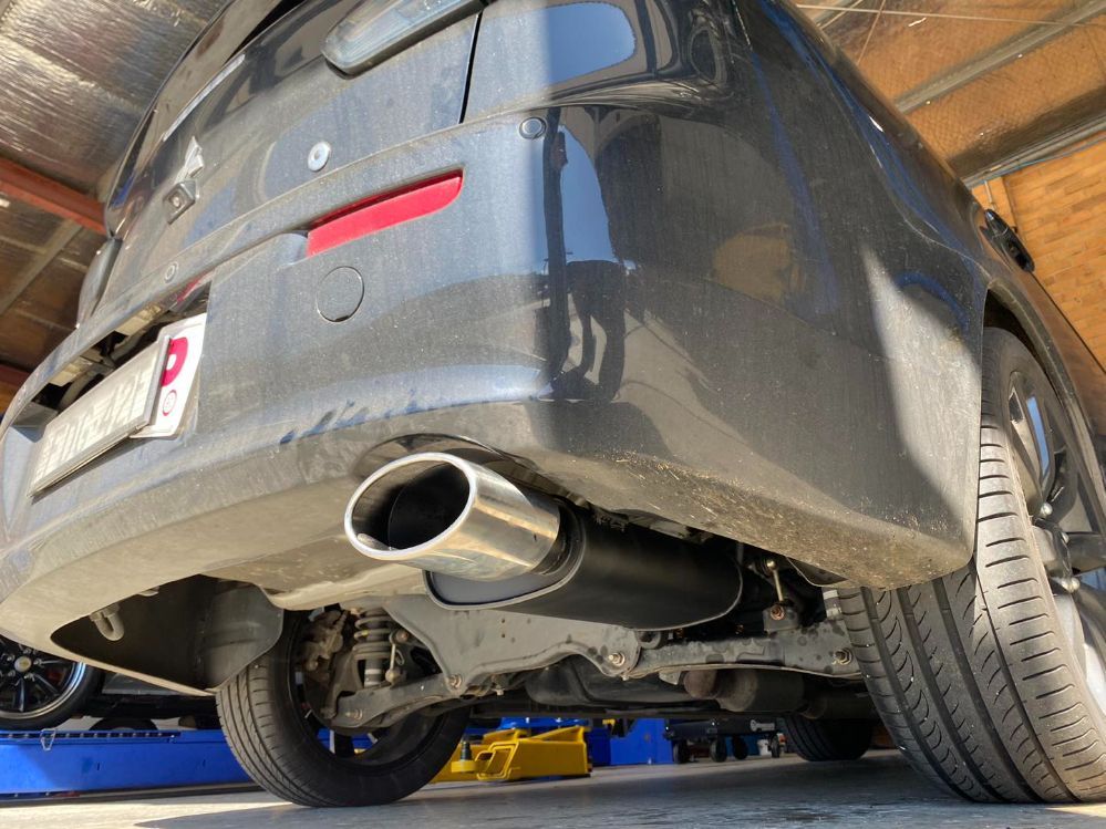 A Black Car With a Stainless Steel Exhaust Pipe is Parked in a Garage — Savins Radiator Service In Tenterfield, NSW