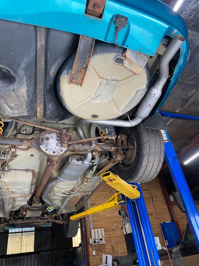 A Blue Car is Sitting on a Lift in a Garage — Savins Radiator Service In Lismore, NSW