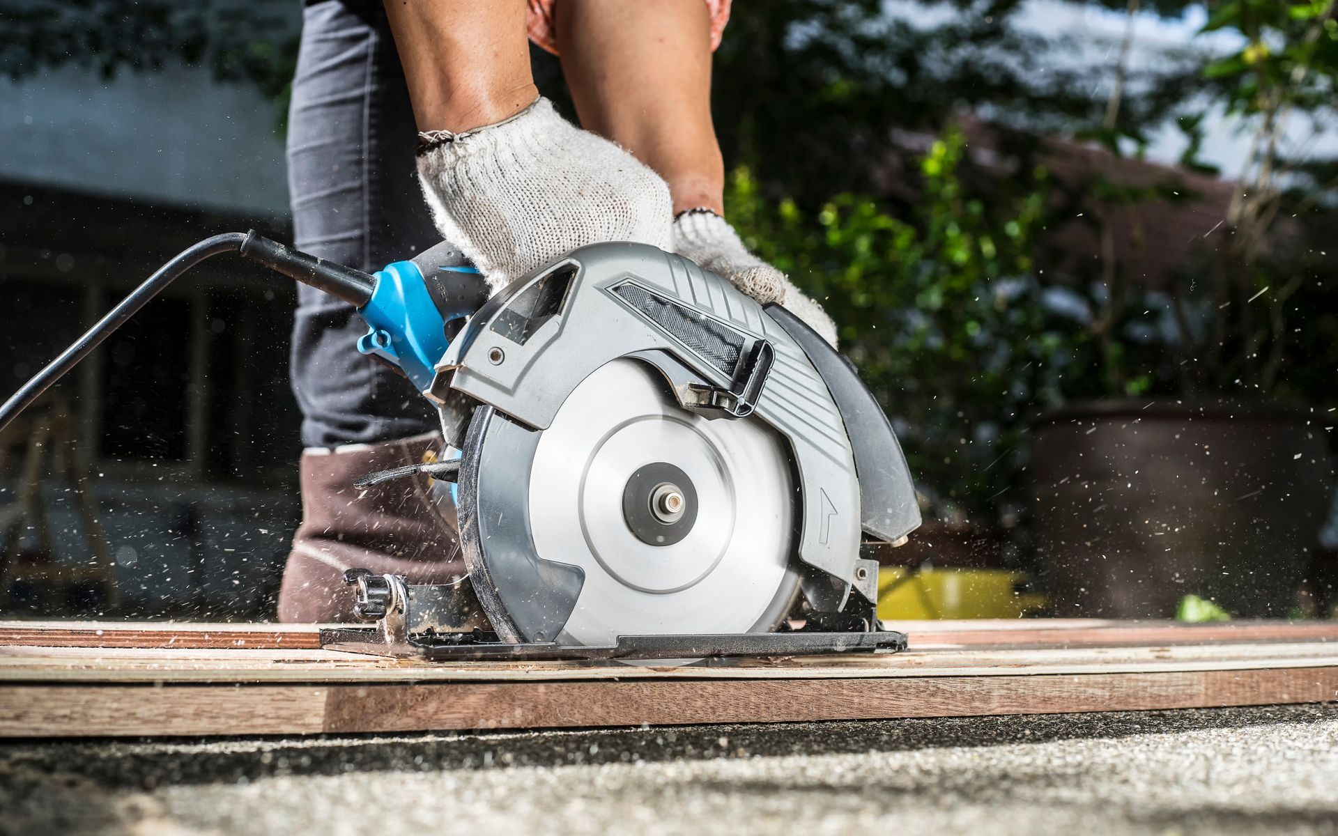 cropped view of a carpenter using a circular saw for cutting wooden boards.