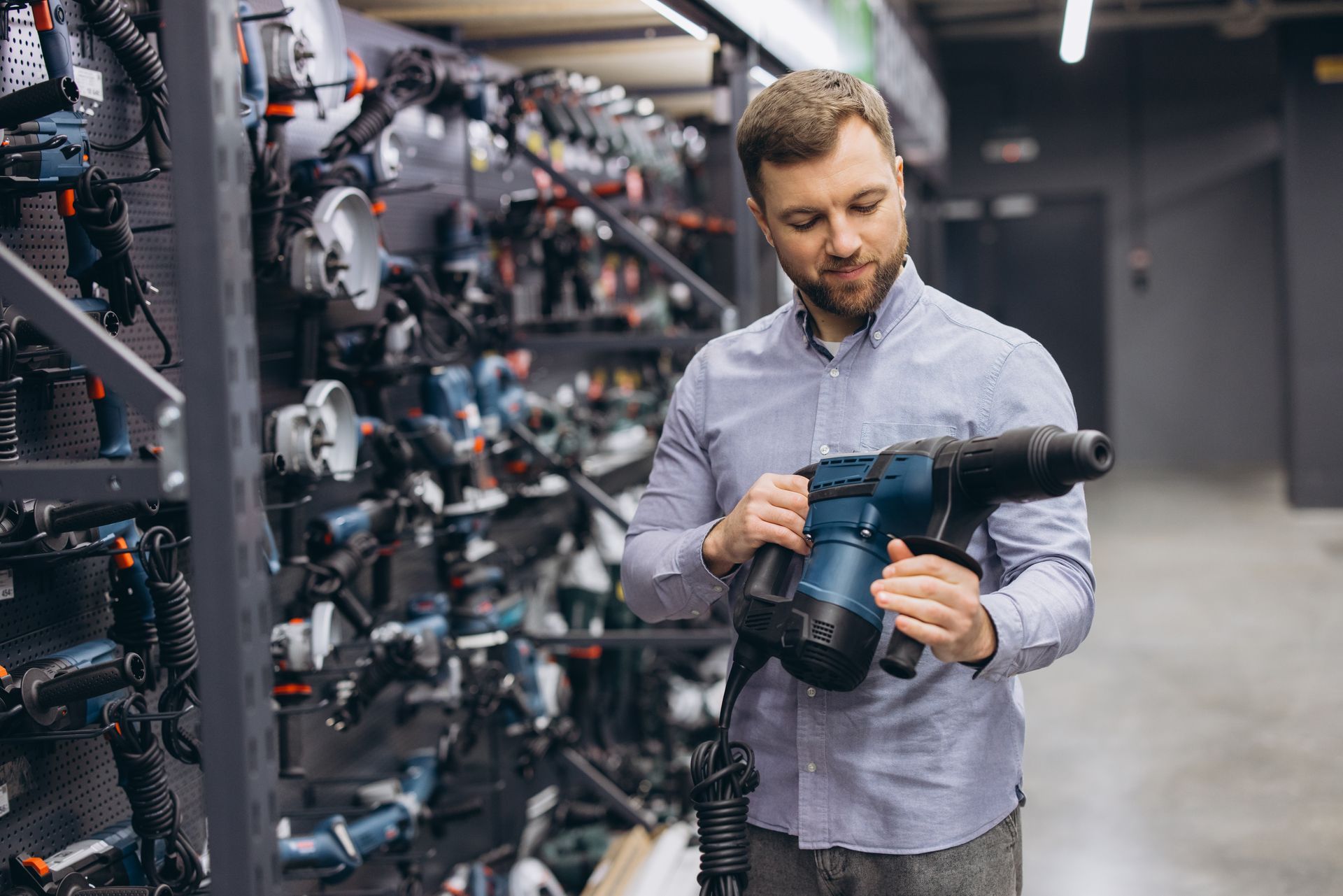 A man shopping for power tools in a hardware store, selecting a hammer drill. A man shopping for power tools in a hardware store, selecting a hammer drill.