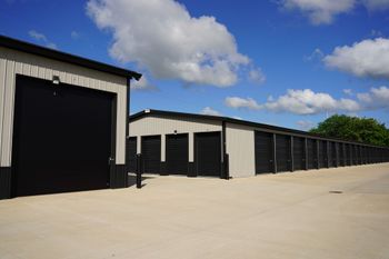 Row of black storage units with white trim under a blue sky with clouds