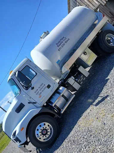 White tanker truck parked outside. Blue sky.
