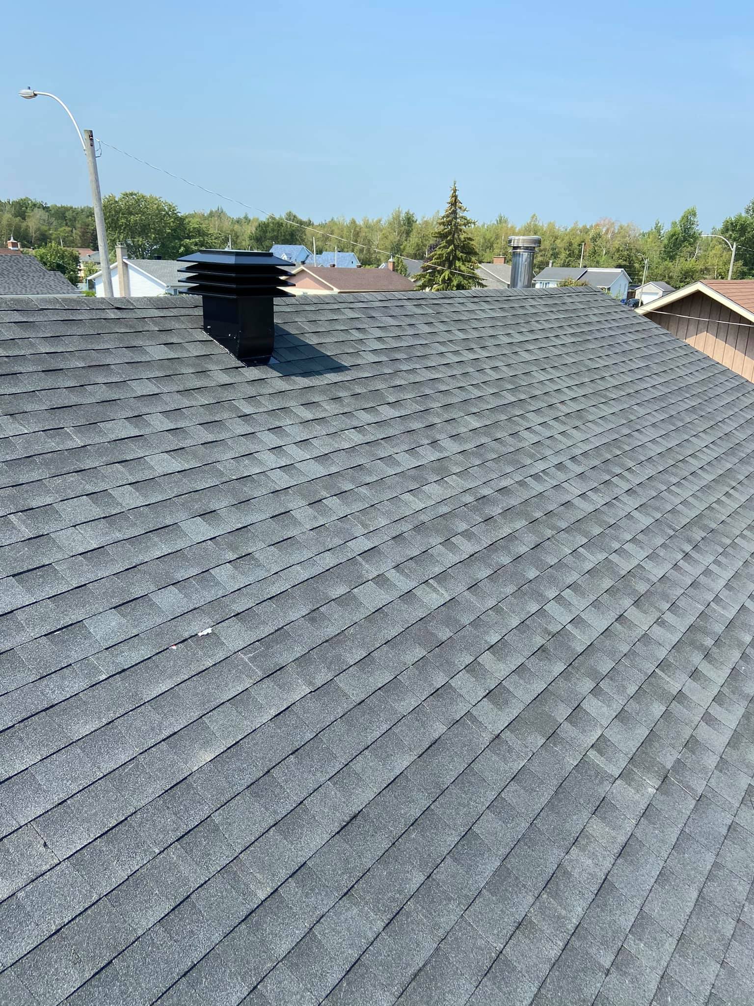 Un toit avec une cheminée et un ciel bleu en arrière-plan.