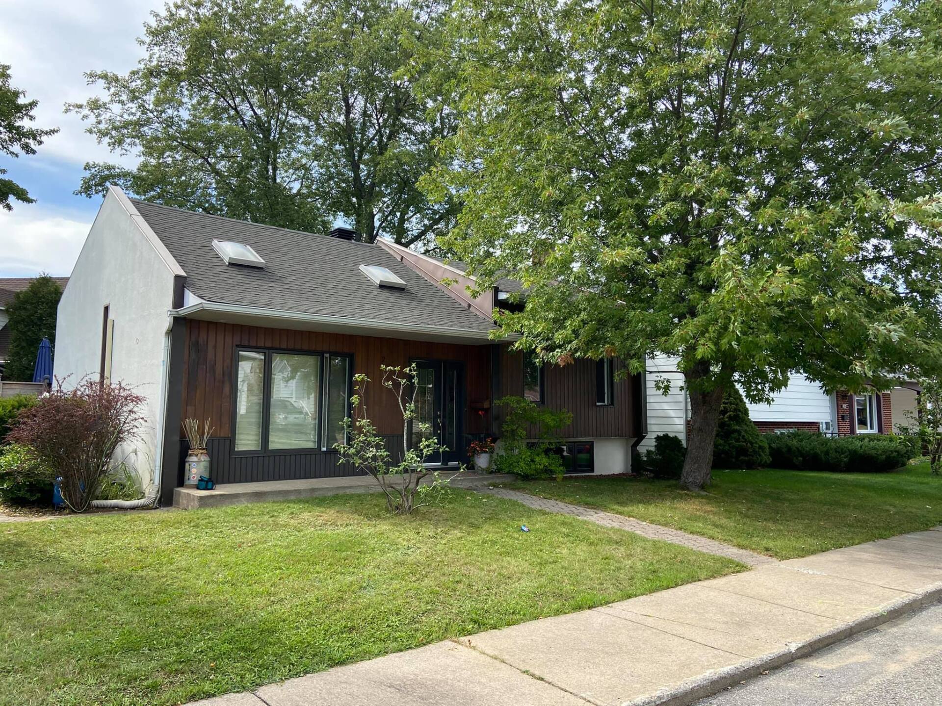 Une petite maison avec beaucoup d'herbe et d'arbres devant.