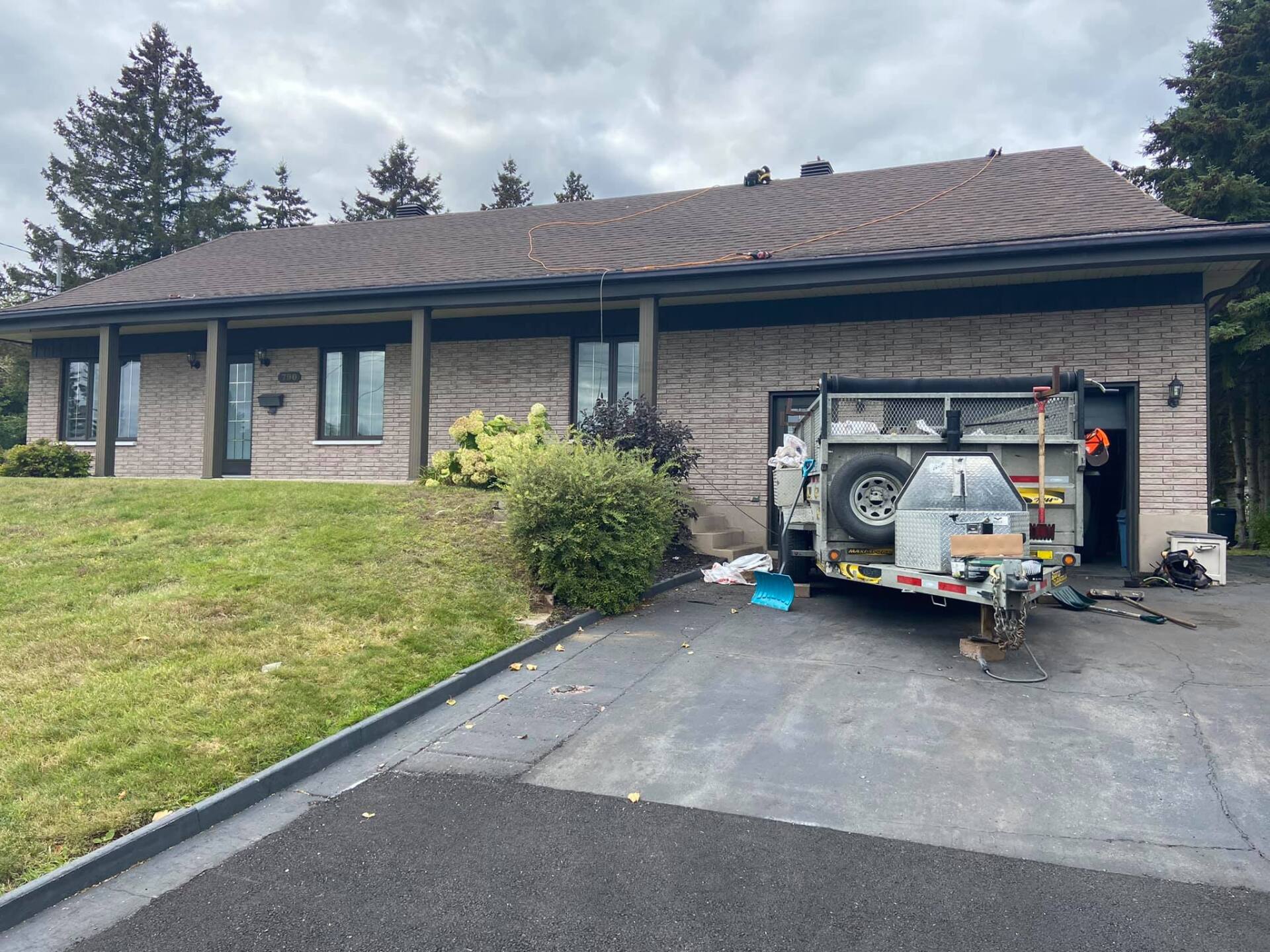 Une caravane est garée devant une maison en brique.