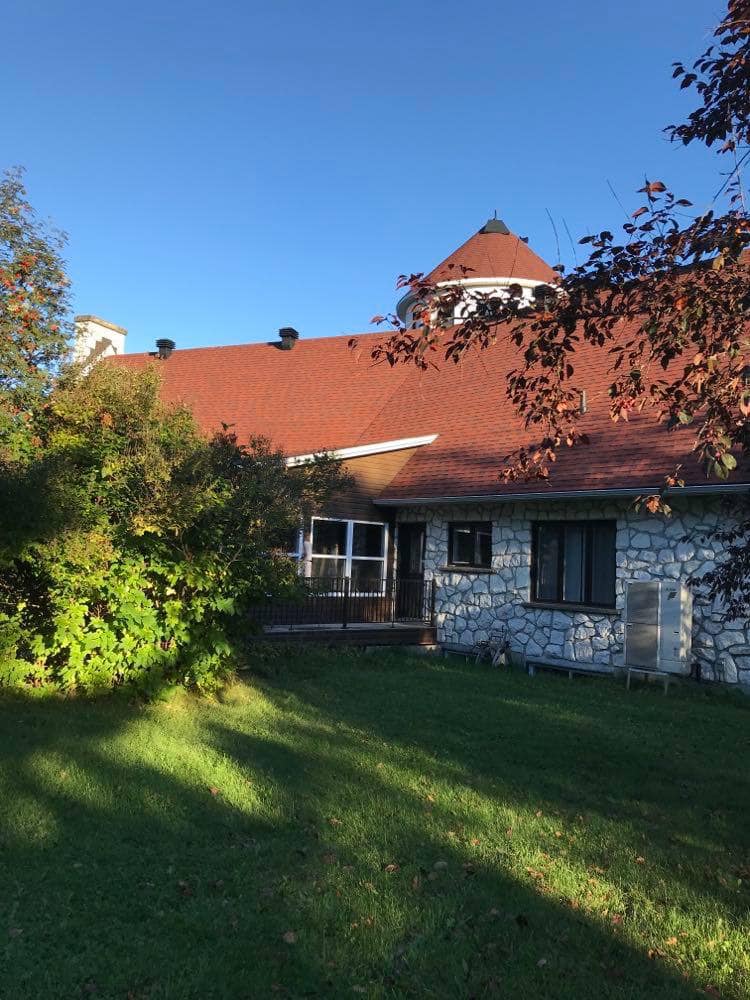 Une maison au toit rouge est entourée d'arbres et d'herbe.