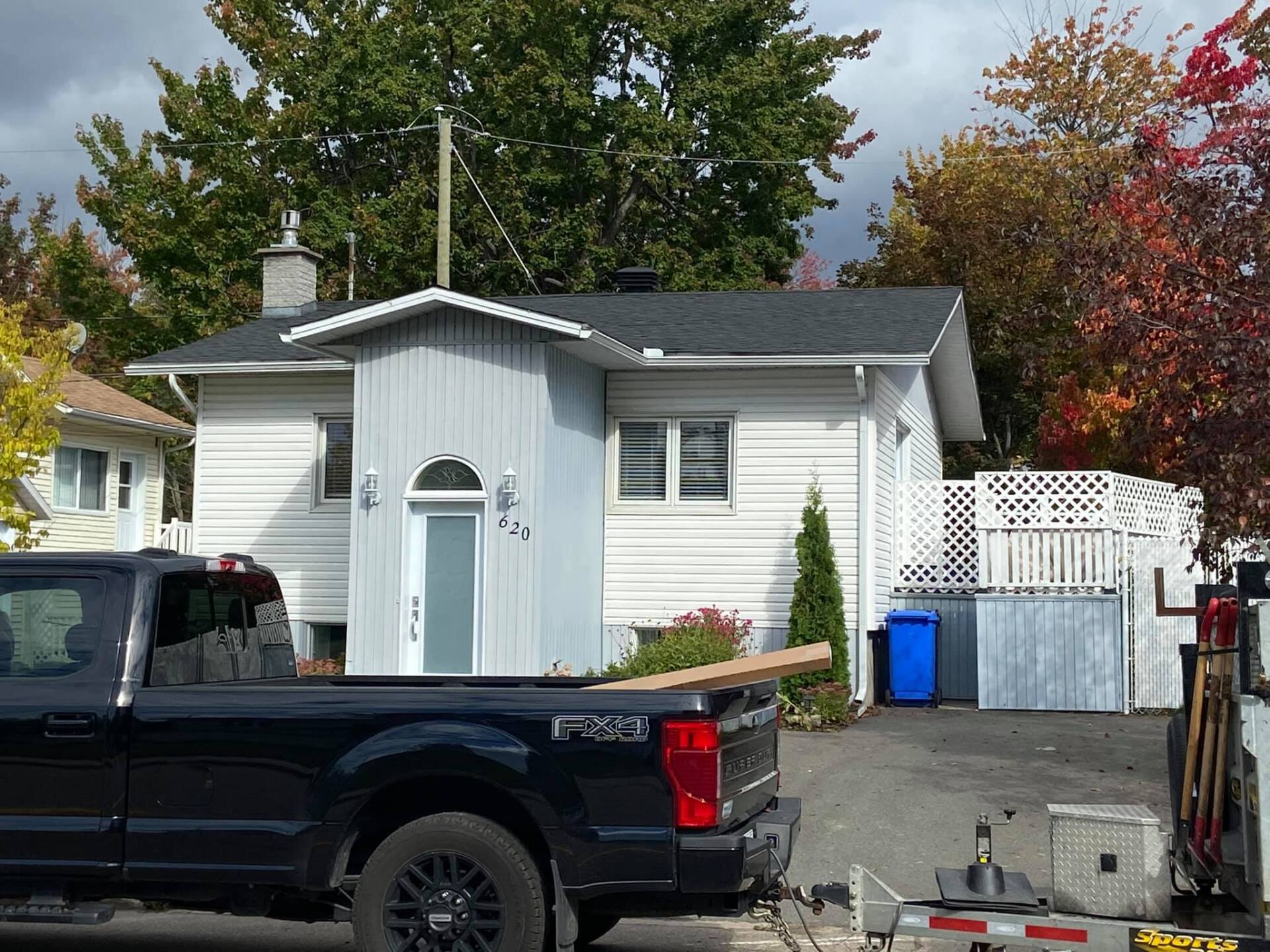 Un camion noir est garé devant une maison blanche