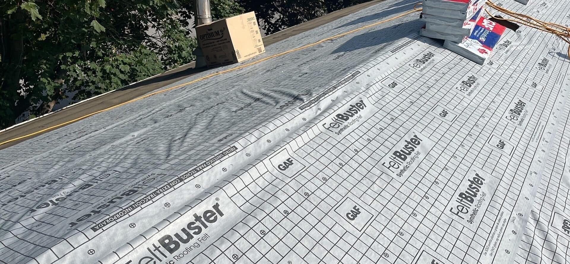 Toiture avec sous-couche, piles de bardeaux, cheminée et arbres.