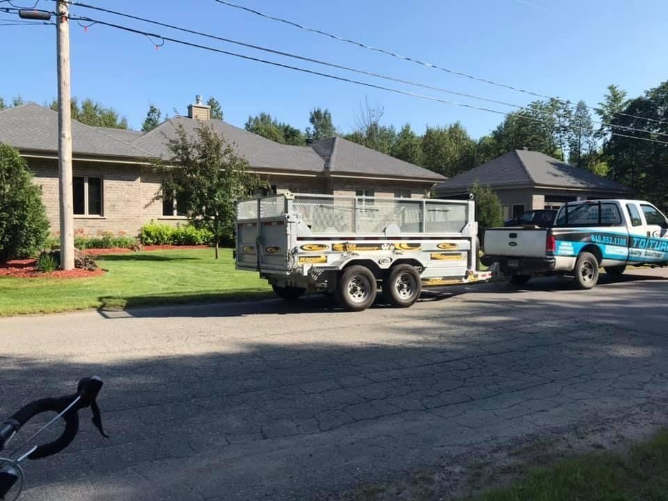 Un camion avec une remorque attachée est garé devant une maison