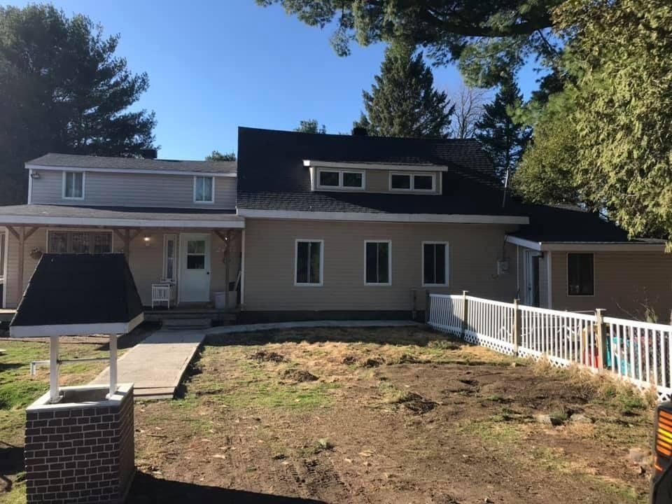 Une maison avec un toit noir et une clôture blanche