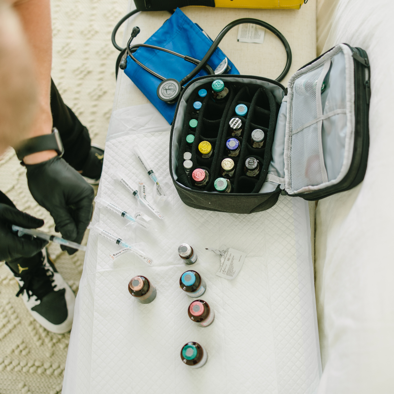 Medical supplies laid out on a white cloth, with bottles, gloves, and a black zip case of vials.