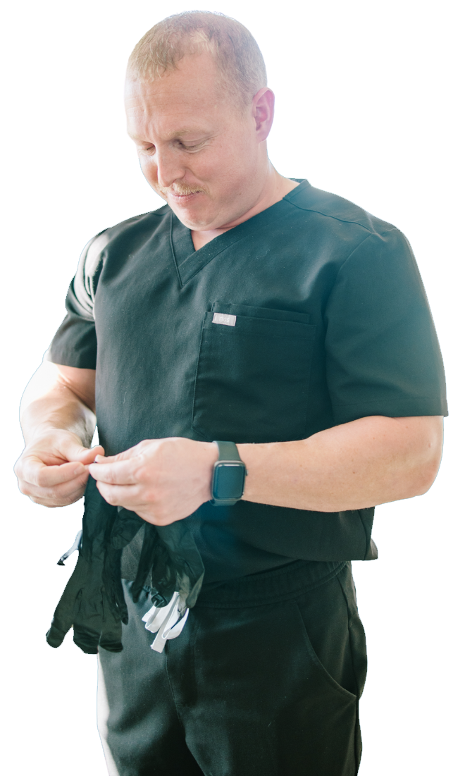 Man in dark uniform adjusting white gloves, standing against a white background.