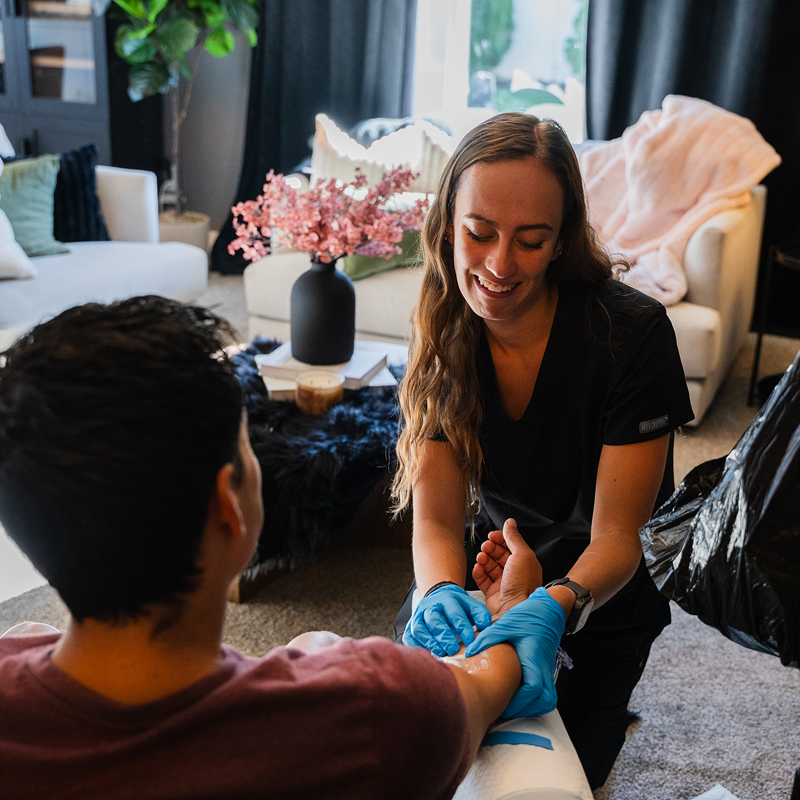 Woman applying blue gloves to another person in a living room setting