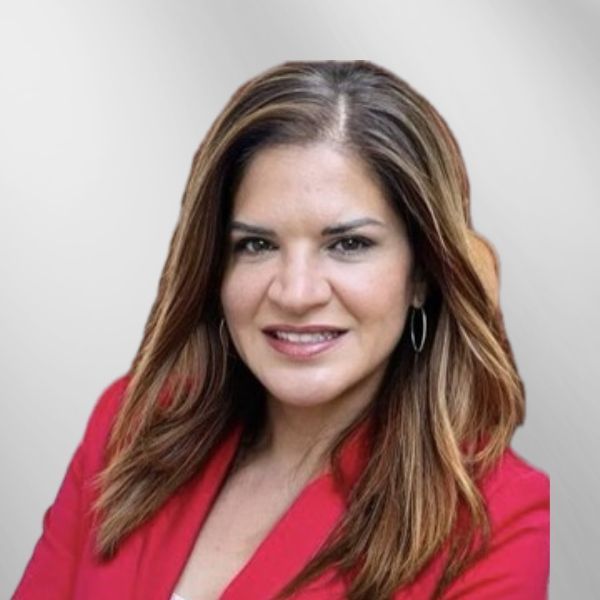 Woman with long brown hair wearing a red blazer smiles against a gray background.