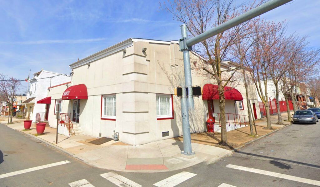 Corner building with red awnings and trees. A street sign is visible.