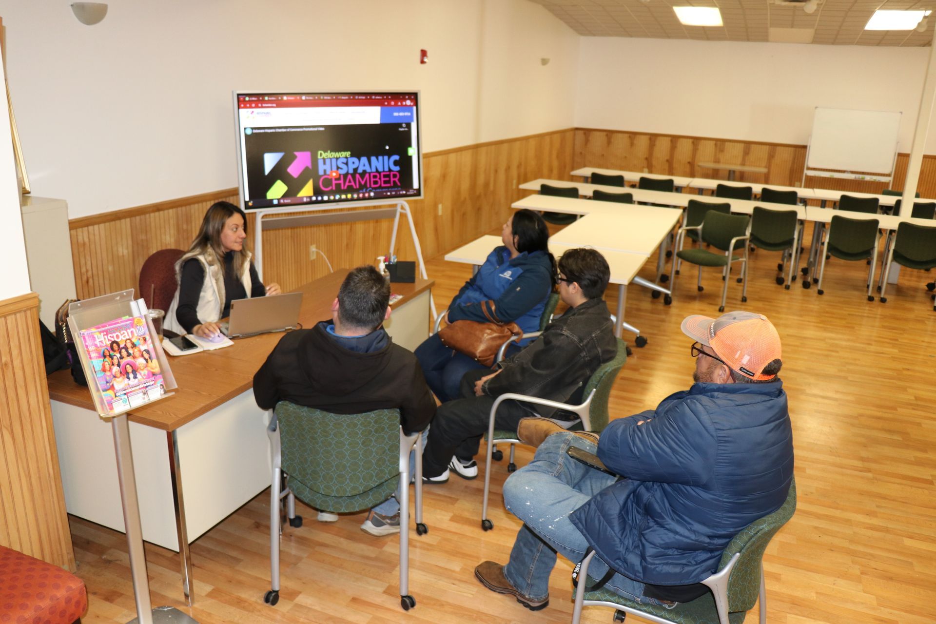Group of people in a room with a presenter and screen displaying Hispanic Heritage.