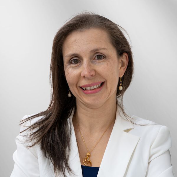 Woman with brown hair in white blazer smiles.