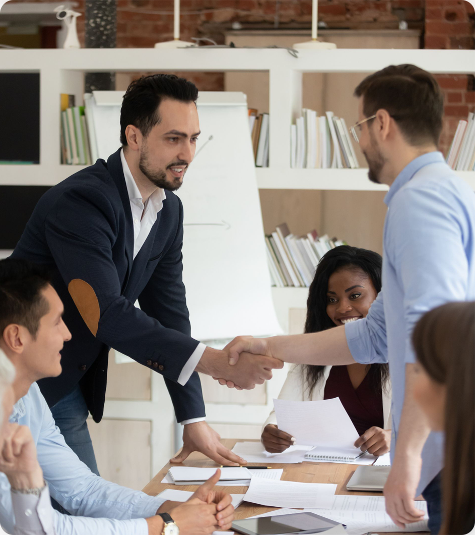 Business people shaking hands in an office meeting; teamwork and agreement.