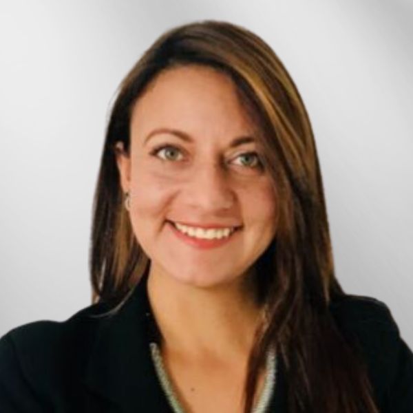 Woman with long brown hair smiling, wearing a black blazer.