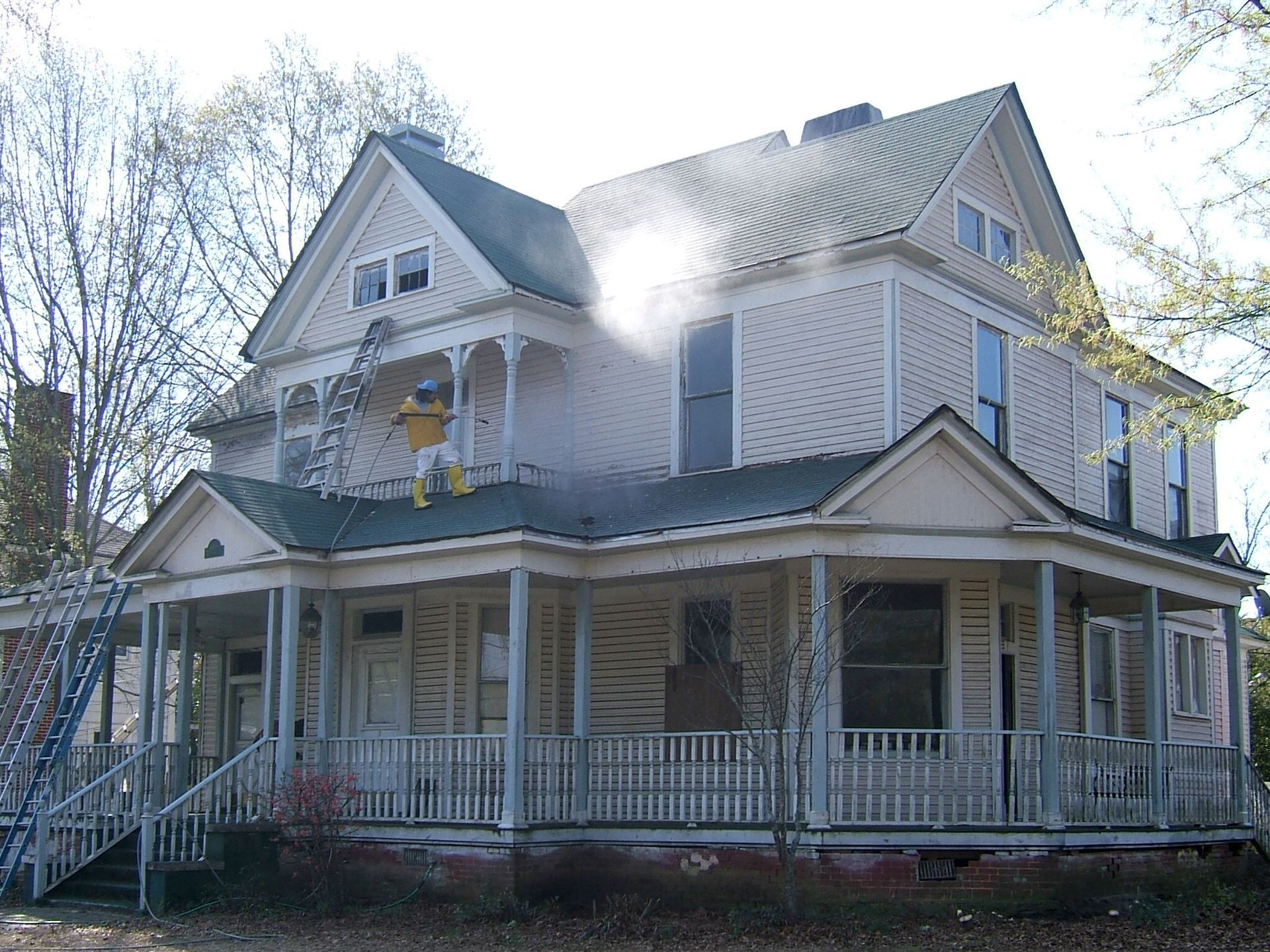 A large white house with a porch and stairs before painting