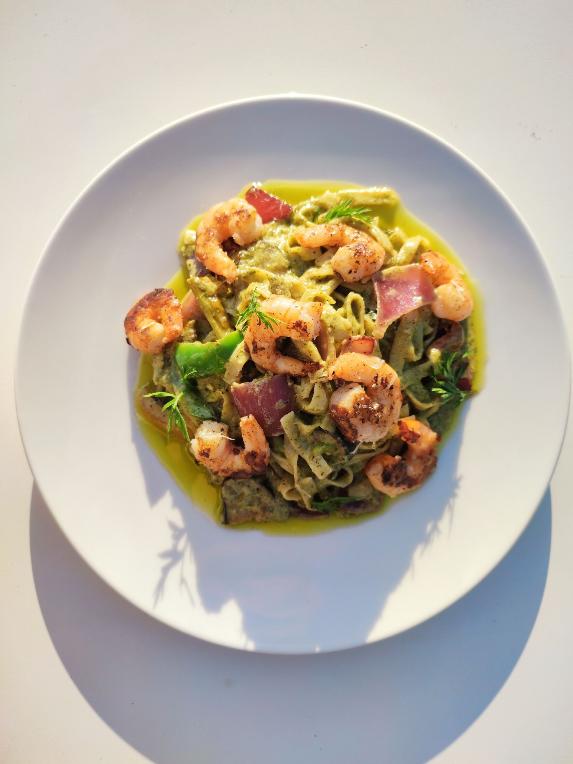 Un plato blanco cubierto con camarones y fideos.