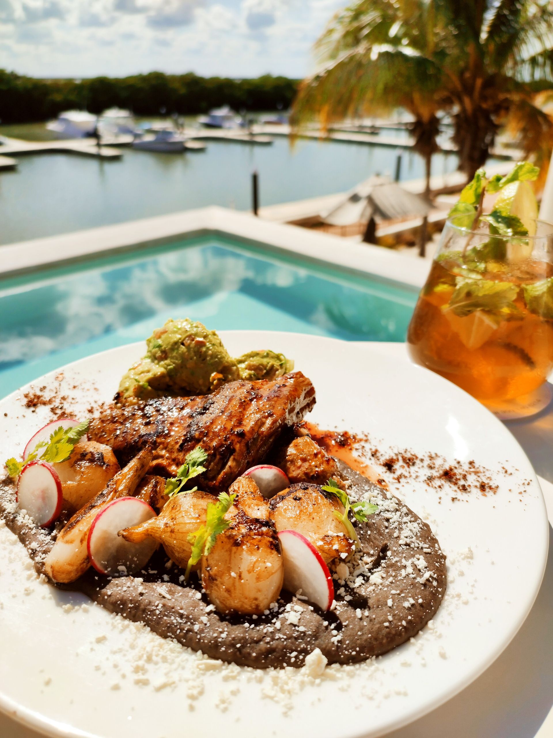 Un plato de comida está en una mesa al lado de una piscina.