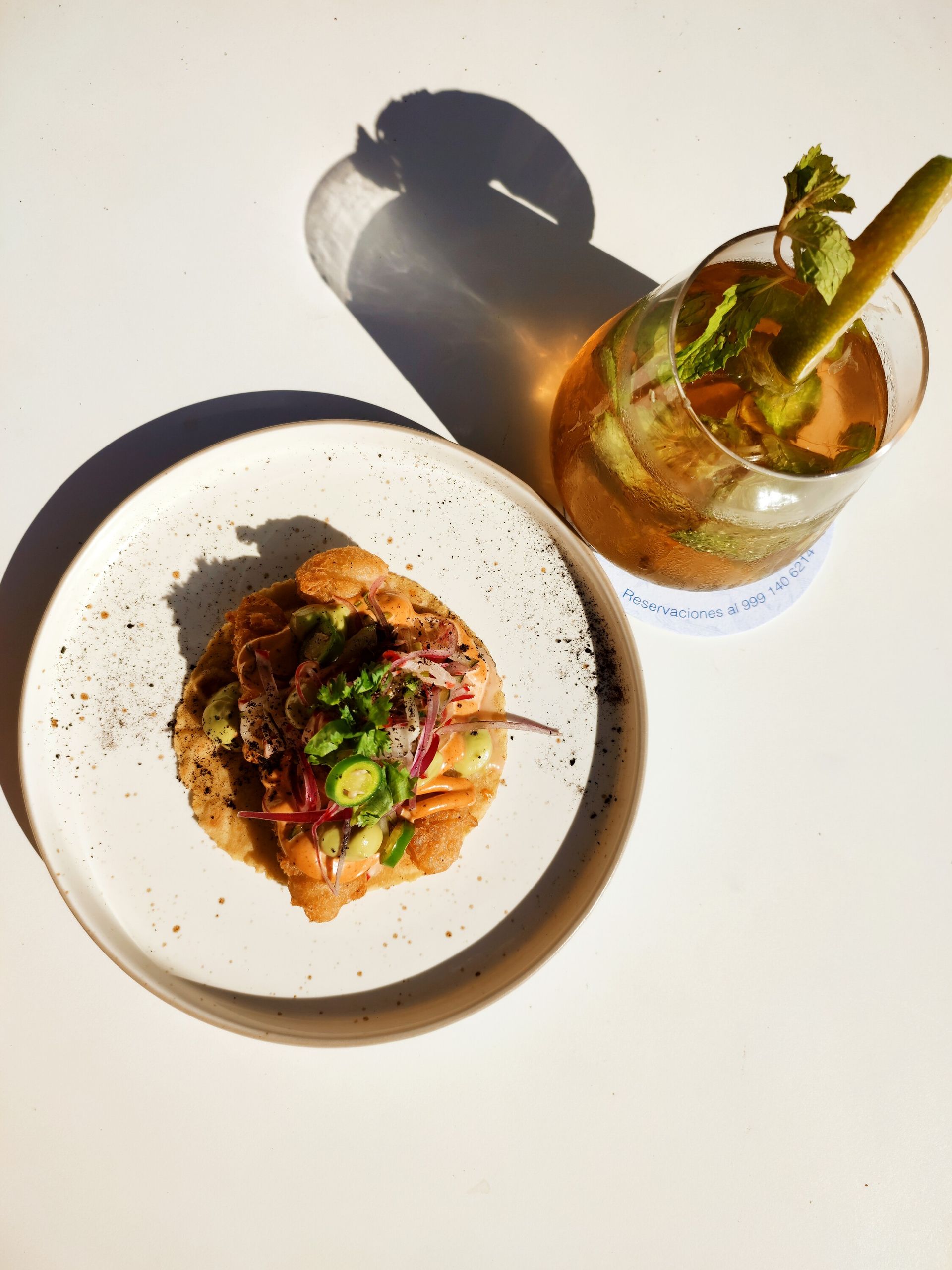 Un plato de comida y un vaso de bebida están sobre una mesa.