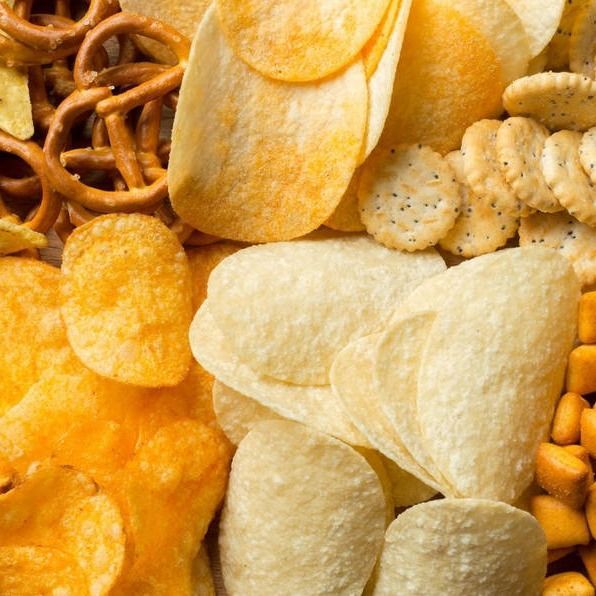Un montón de patatas fritas, pretzels, maíz y galletas saladas.