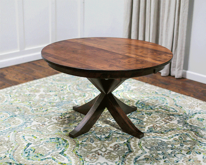 A round wooden table is sitting on top of a rug in a living room.