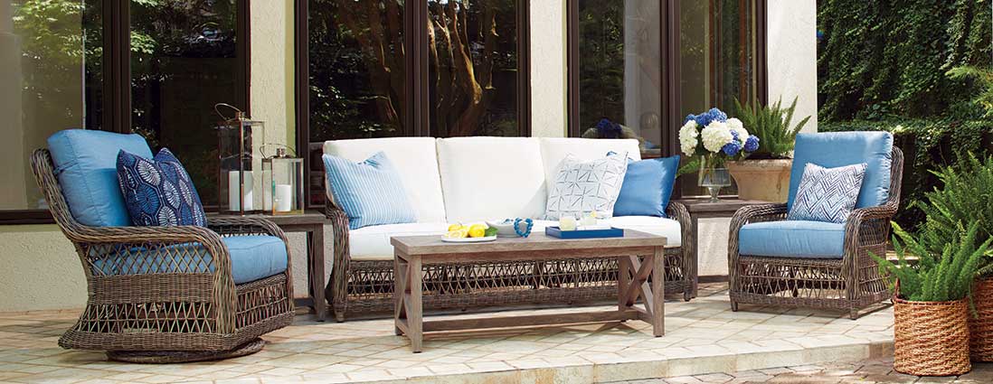 A patio with a couch , chairs , and a coffee table.