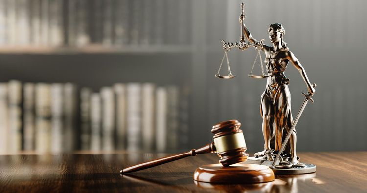 Judge’s gavel and scales of justice on a wooden desk, with books blurred in the background