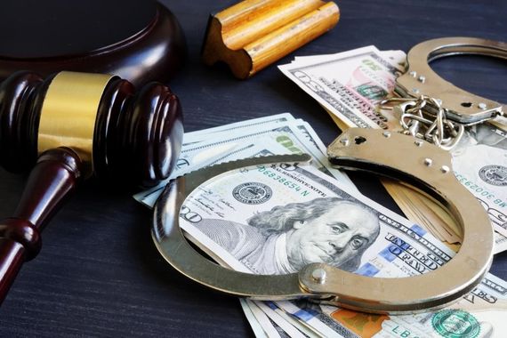 Judge’s gavel, handcuffs, and cash on a desk, suggesting an arrest or legal case.