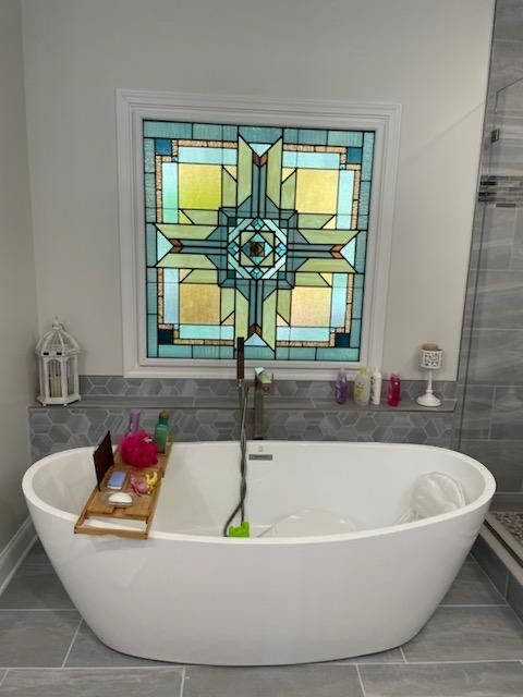 A bathtub in a bathroom with a stained glass window above it